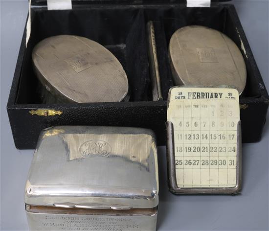 A silver cigarette box with masonic related inscription, a caed pair of silver clothes brushes and a desk calendar.